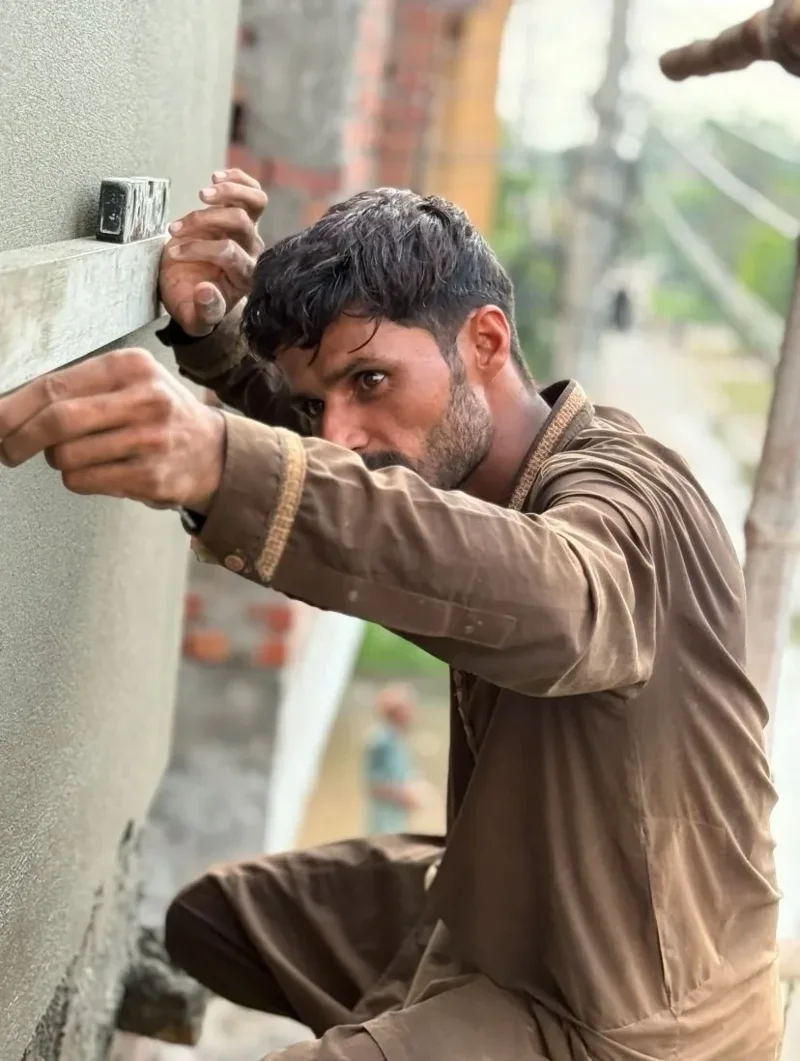Paracha Construction mason checking a plastered wall with a spirit level